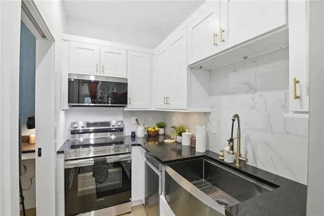 a kitchen with white cabinets a sink and stainless steel appliances