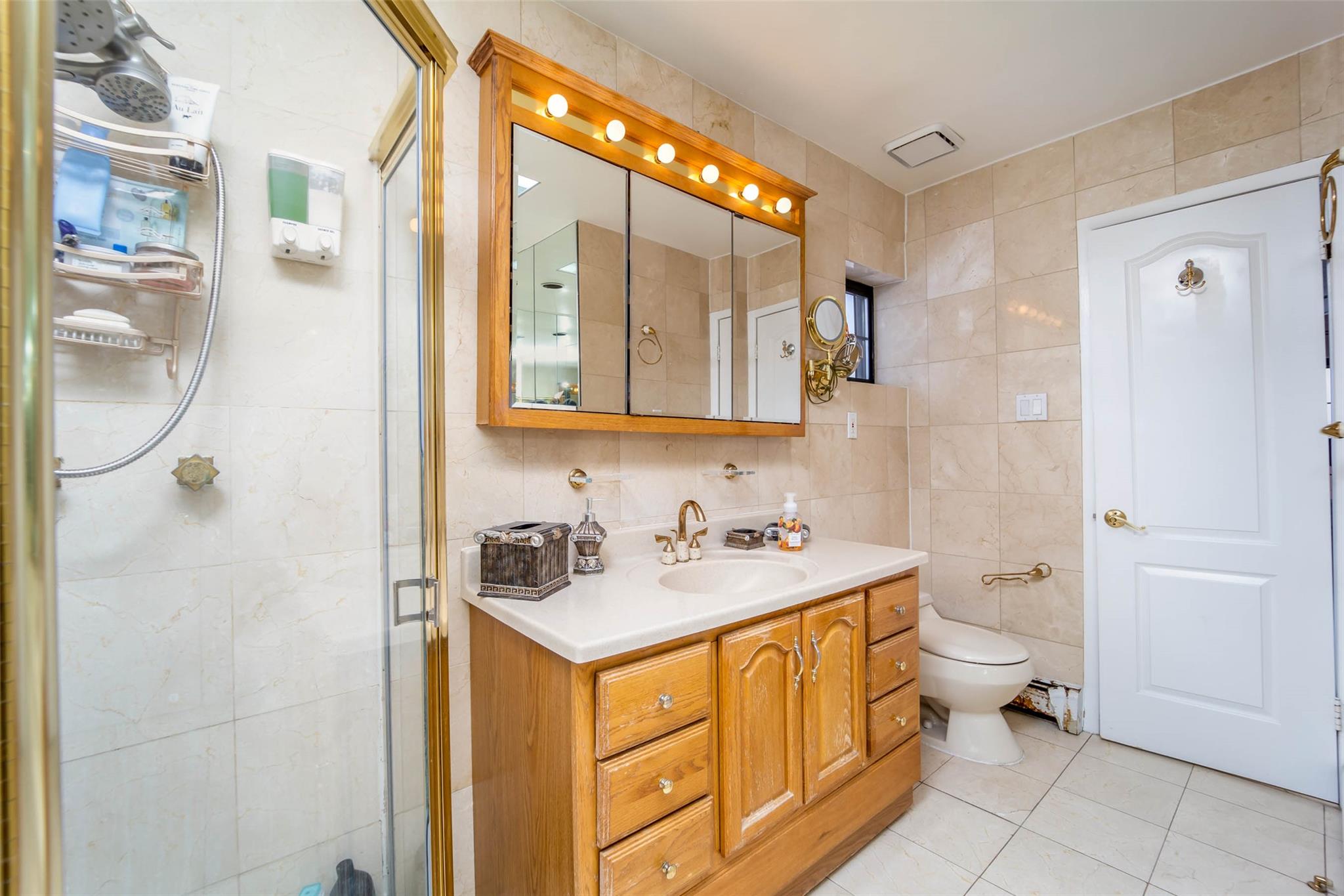 509 Julius Road Queens, NY 11356 - Photo 18 of 26 PRIMARY BATHROOM SUITE Bathroom with tile walls, tile patterned floors, vanity, a stall shower, and toilet