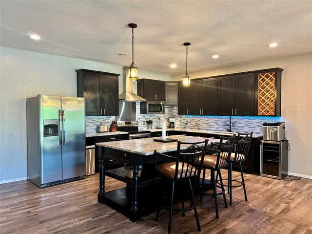 a kitchen with stainless steel appliances a dining table chairs stove and refrigerator