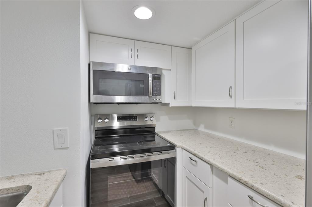 4736 Jasper Drive, Unit 103 New Port Richey, FL 34652 - Photo 14 of 41 a kitchen with granite countertop a stove and a sink