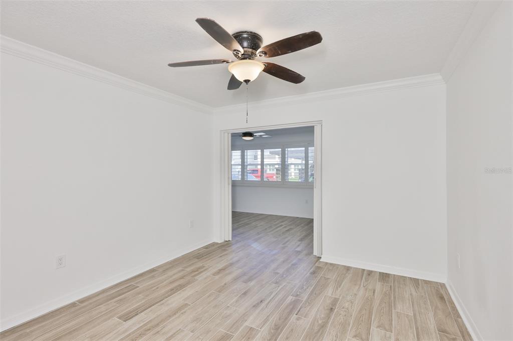 4736 Jasper Drive, Unit 103 New Port Richey, FL 34652 - Photo 23 of 41 an empty room with wooden floor and ceiling fan