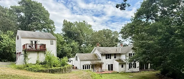 a view of a white house with a big yard and large tree