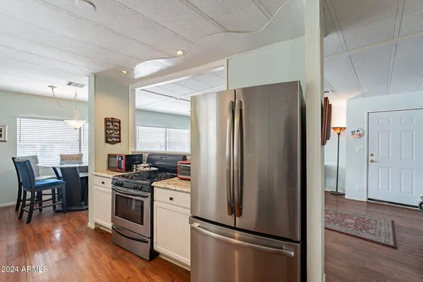 a kitchen with stainless steel appliances a refrigerator a stove a sink a dining table and chairs