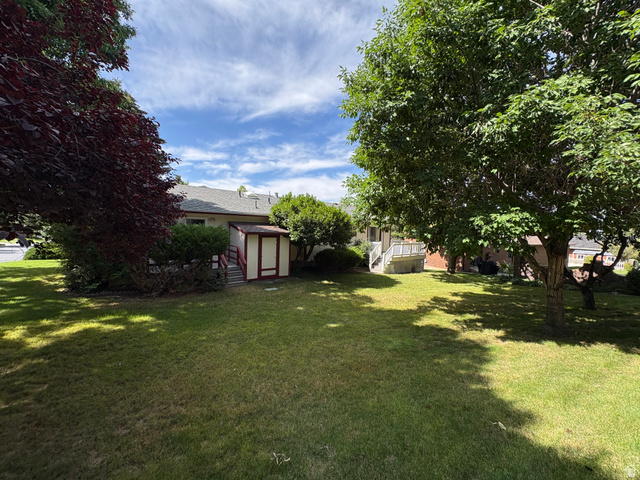 595 Meadowlark Road Orem, UT 84097 - Photo 71 of 87 Expansive green lawn with mature trees and a detached shed featuring red trim