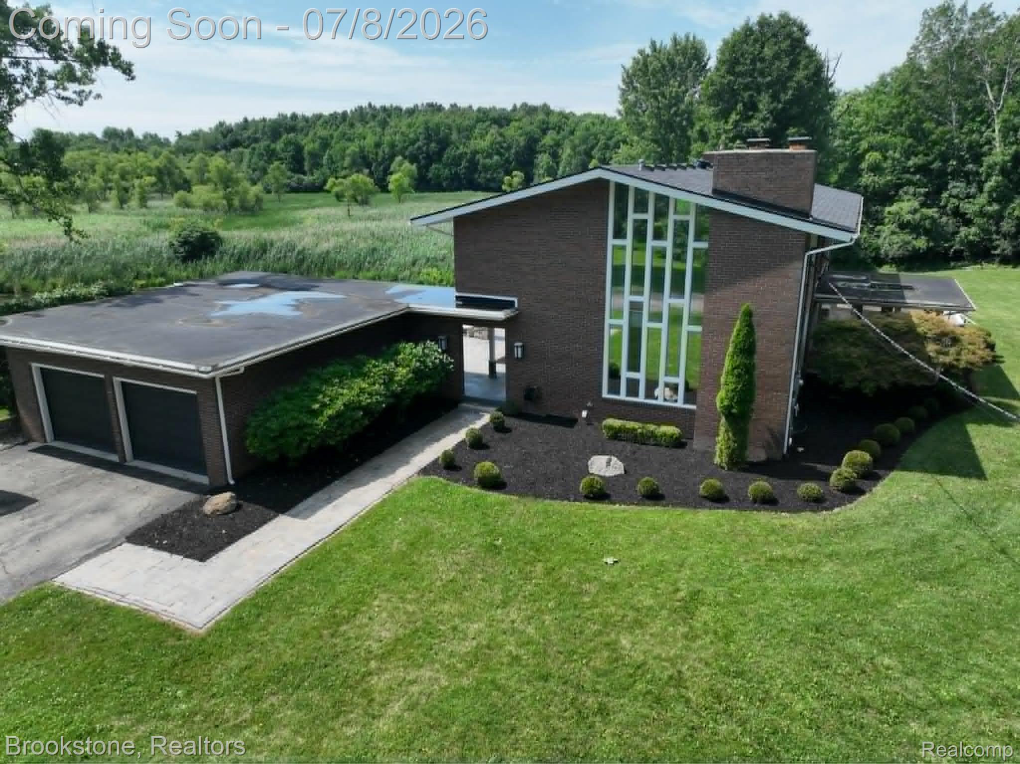 4140 South Henderson Road Davison, MI 48423 - Photo 1 of 98 Brick exterior with a prominent vertical window array, two-car garage, manicured lawn, and mature landscaping