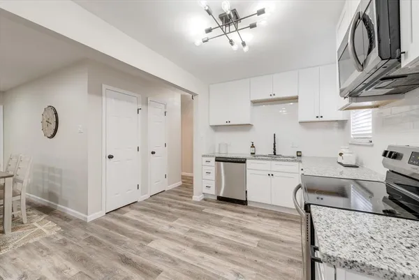 a kitchen with granite countertop a sink cabinets stainless steel appliances and a counter top space