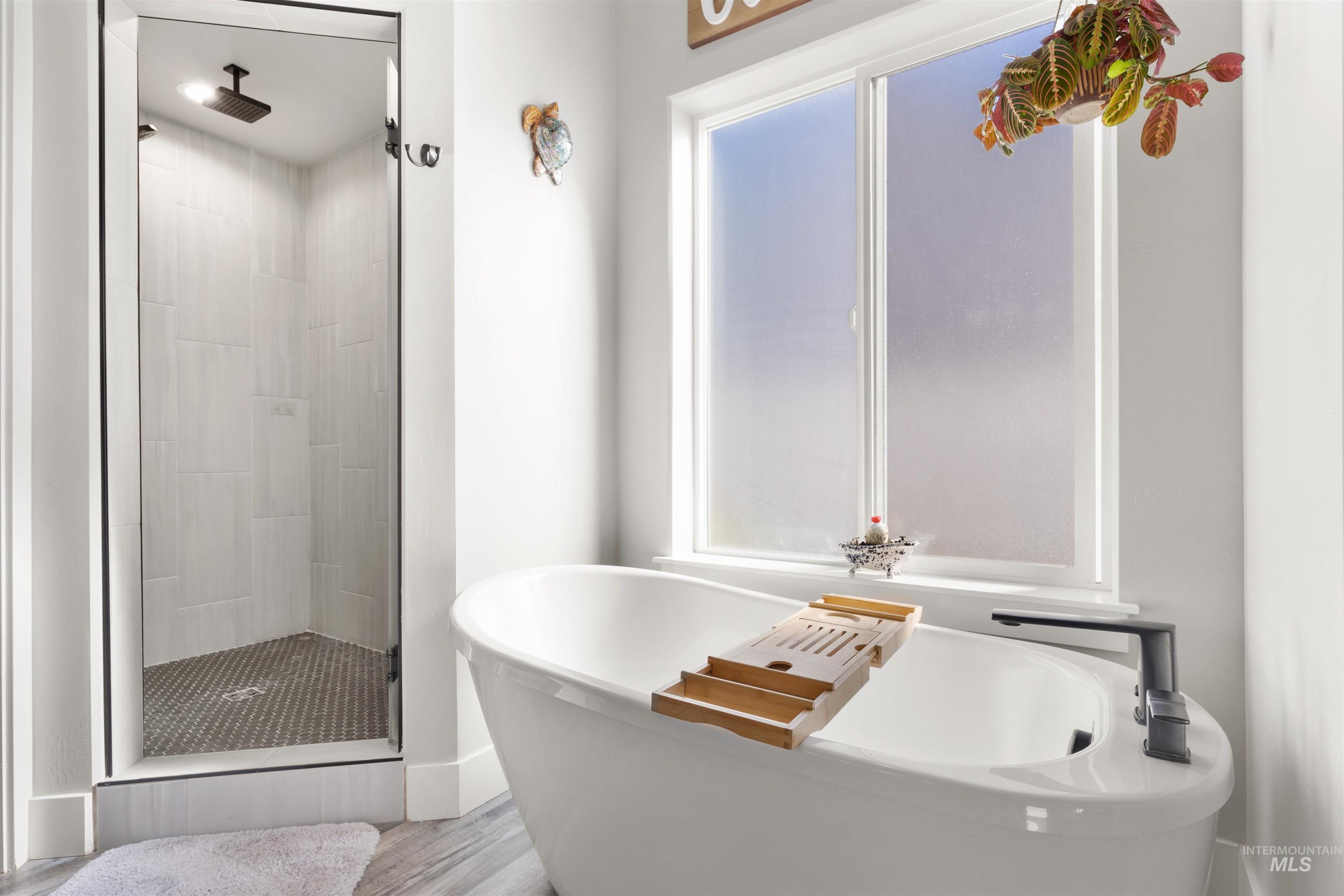 2958 Sunlight Road Twin Falls, ID 83301 - Photo 20 of 40 Freestanding soaking tub with a modern black faucet, alongside a glass-enclosed shower with tiled walls and a mosaic floor