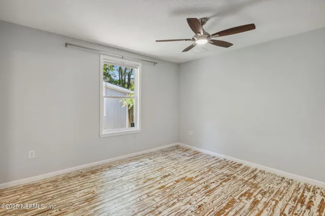 a view of an empty room with window and wooden floor