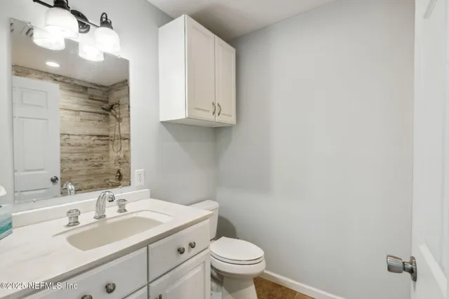 a bathroom with a granite countertop sink a toilet and a mirror