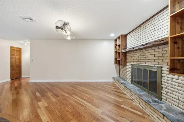 a view of a big room with wooden floor and windows