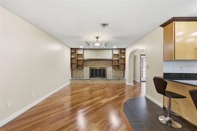 a view of an empty room with wooden floor and ceiling fan