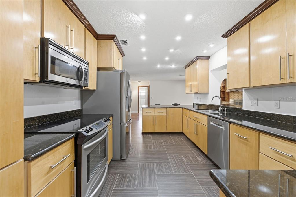 8123 River Country Drive Weeki Wachee, FL 34607 - Photo 36 of 61 a kitchen with stainless steel appliances kitchen island granite countertop a stove a sink and a refrigerator