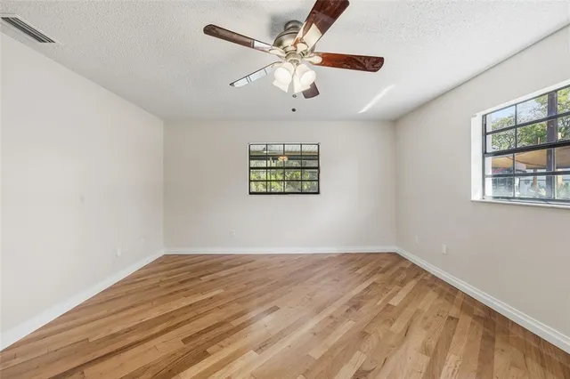 a view of a big room with wooden floor and windows