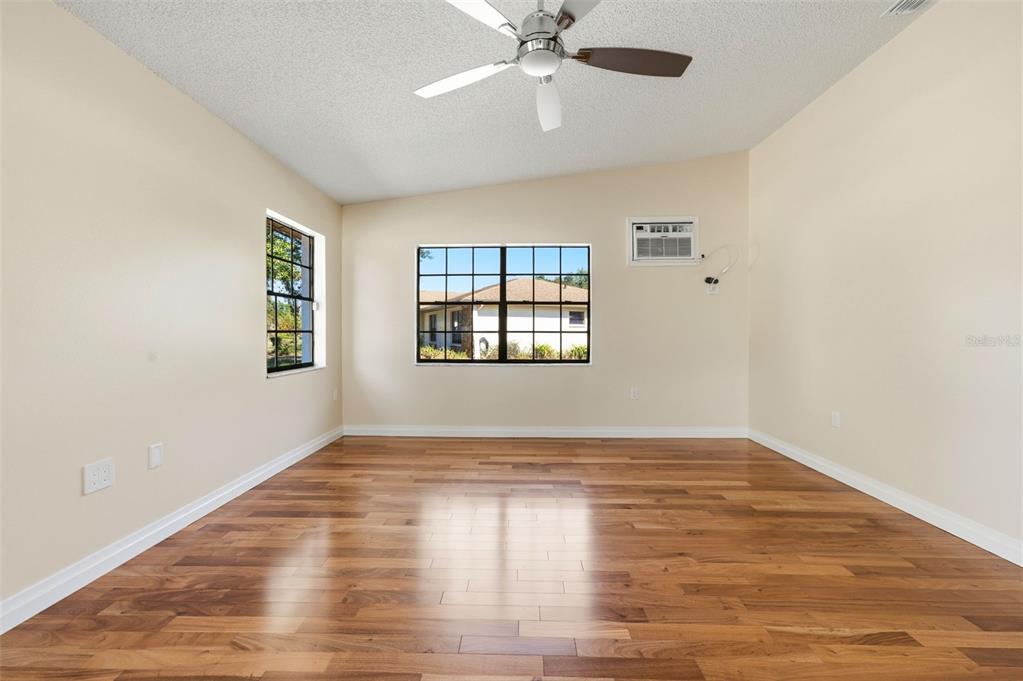 8123 River Country Drive Weeki Wachee, FL 34607 - Photo 54 of 61 an empty room with wooden floor chandelier fan and windows