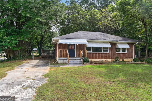 a front view of a house with a garden and trees