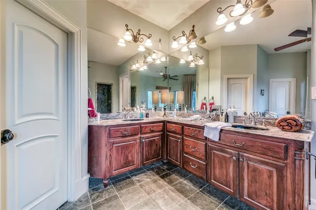 a spacious bathroom with a granite countertop sink a large mirror and vanity