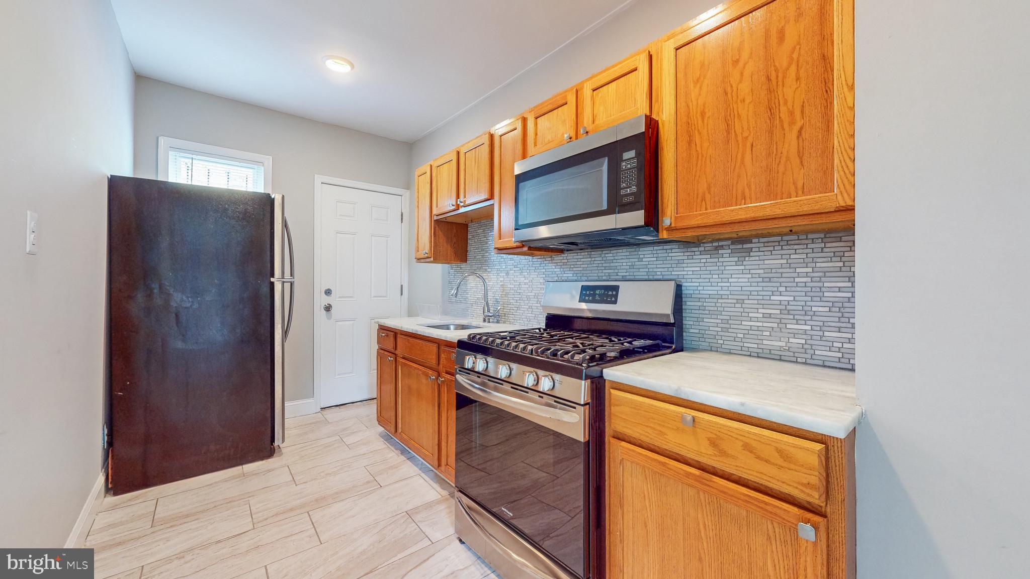 812 McCabe Avenue Baltimore, MD 21212 - Photo 10 of 18 a kitchen with stainless steel appliances granite countertop a stove a microwave and a refrigerator
