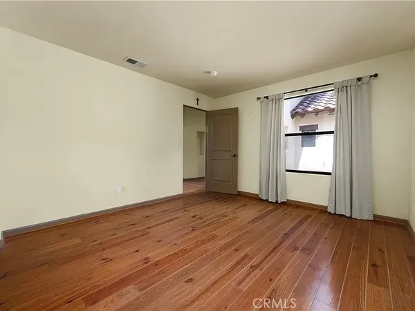 a view of an empty room with closet and wooden floor