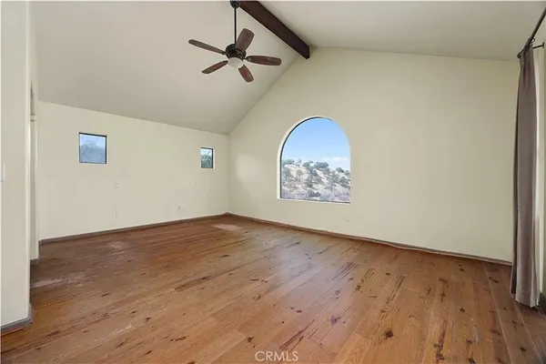 an empty room with wooden floor fan and windows