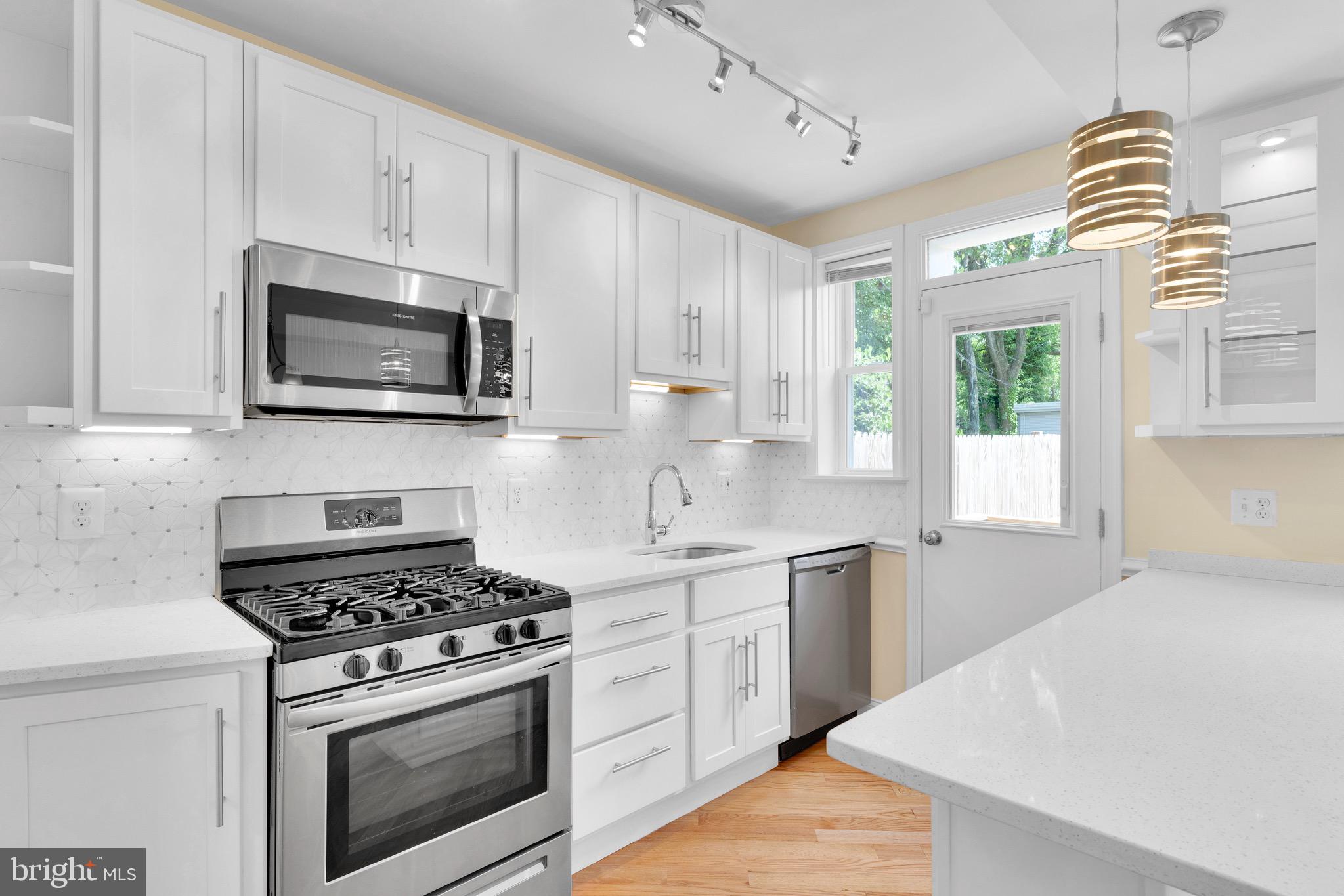 a kitchen with cabinets stainless steel appliances a sink a stove and a window