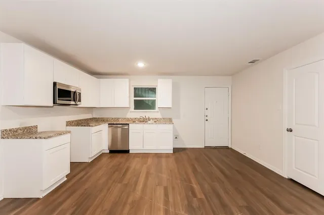 a kitchen with a hard wood floor white cabinets and white appliances