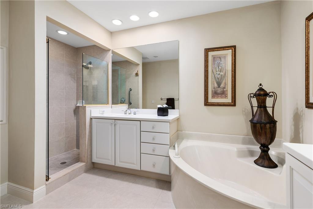 7837 Hawthorne Drive, Unit 1101 Naples, FL 34113 - Photo 13 of 26 a bathroom with a tub sink and mirror