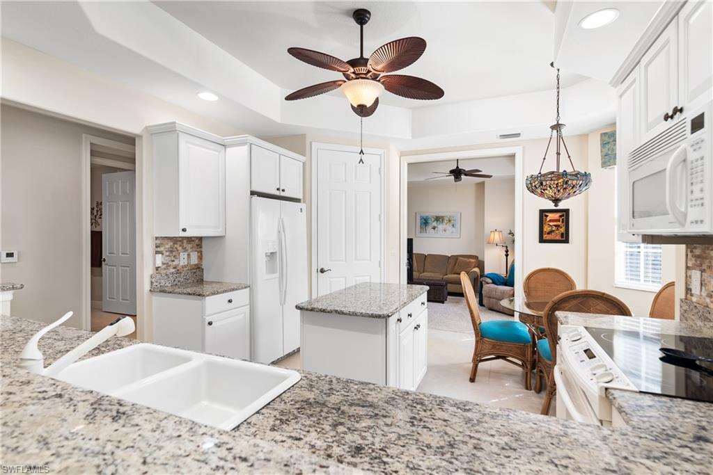 7837 Hawthorne Drive, Unit 1101 Naples, FL 34113 - Photo 7 of 26 a living room with granite countertop furniture a fireplace and a chandelier