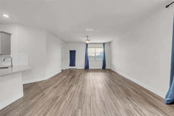 a view of an empty room with window and wooden floor