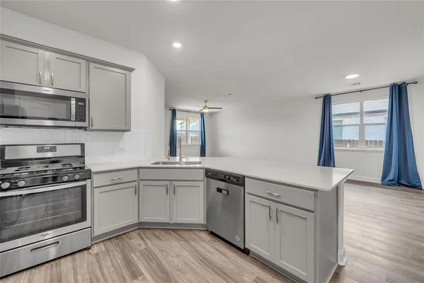 a kitchen with white cabinets appliances and wooden floor
