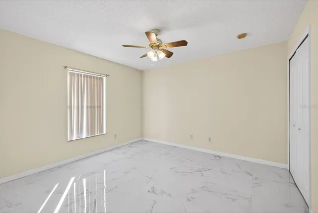 an empty room with windows and fan