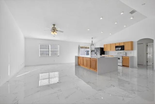a living room with stainless steel appliances kitchen island granite countertop a sink cabinets and window