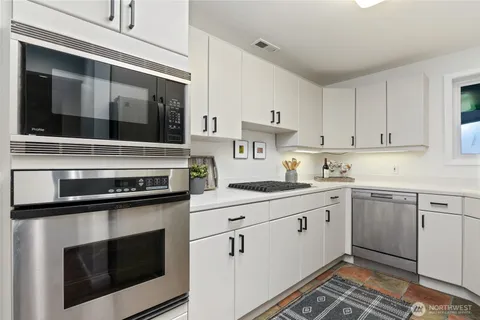 a kitchen with granite countertop white cabinets and white appliances