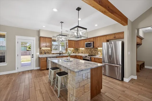 a kitchen with stainless steel appliances granite countertop a refrigerator a sink dishwasher a stove and white countertops with wooden floor