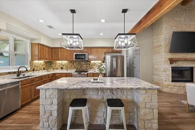 a kitchen with kitchen island granite countertop a sink a counter space appliances and cabinets