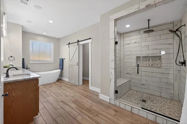 a bathroom with a tub shower sink and mirror