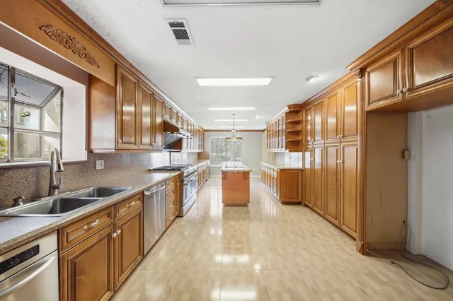 a large kitchen with stainless steel appliances granite countertop a lot of counter space and a sink
