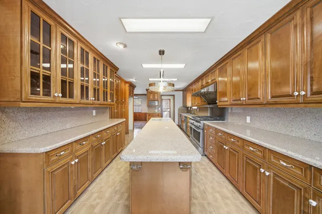 a large kitchen with stainless steel appliances granite countertop lots of counter top space and wooden floor