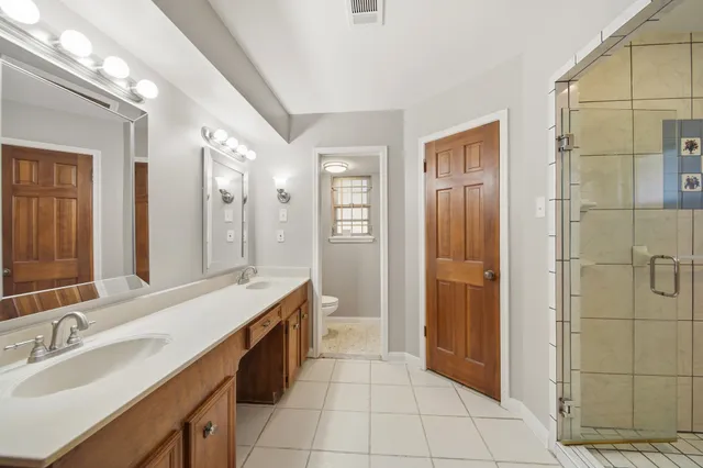 a spacious bathroom with a double vanity sink a mirror and a shower