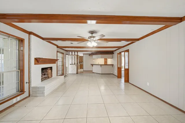 a view of a livingroom with a fireplace a chandelier fan and windows