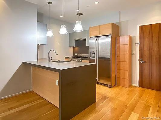 2280 Frederick Douglass Boulevard Manhattan, NY 10027 - Photo 11 of 16 Kitchen with modern cabinets, a peninsula, pendant lighting, stainless steel built in refrigerator, and light wood finished floors