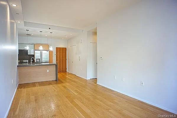 2280 Frederick Douglass Boulevard Manhattan, NY 10027 - Photo 16 of 16 Kitchen with hanging light fixtures, open floor plan, light wood-type flooring, stainless steel refrigerator with ice dispenser, and a peninsula