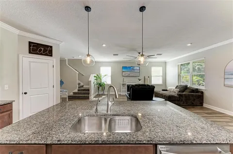 a kitchen with granite countertop kitchen island stainless steel appliances a table chairs sink refrigerator and microwave