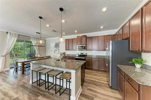 a kitchen with stainless steel appliances granite countertop sink stove refrigerator and cabinets