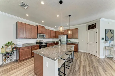 a kitchen with stainless steel appliances granite countertop a sink a stove and a wooden floors