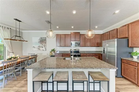 a kitchen with stainless steel appliances granite countertop a kitchen island a stove a table and chairs