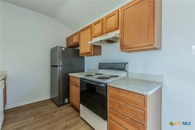 a kitchen with a refrigerator and a stove top oven