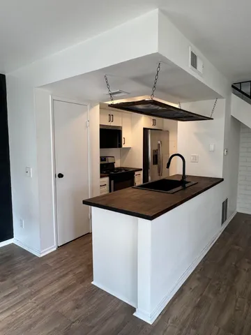 a kitchen with stainless steel appliances a sink and wooden floor