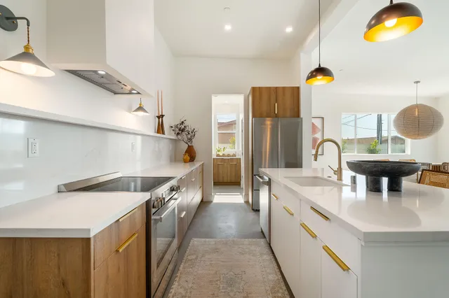 a kitchen with kitchen island granite countertop a sink a counter top space and stainless steel appliances
