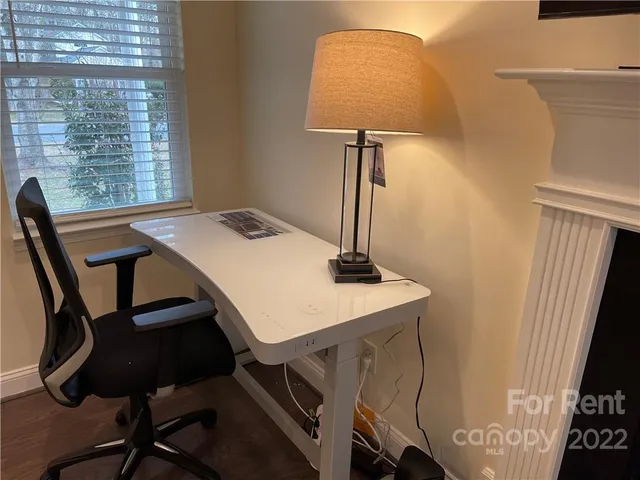 a view of a workspace with furniture and a window