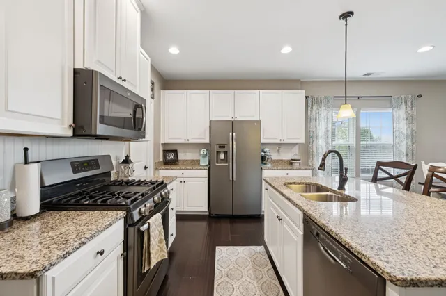 a view of a dining room and livingroom with furniture wooden floor a rug a fireplace and a chandelier